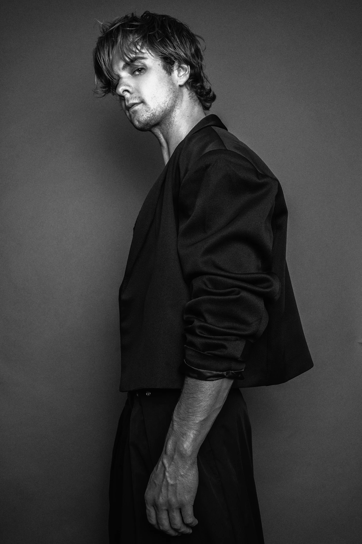 Jake Crossman standing in profile in a black blazer