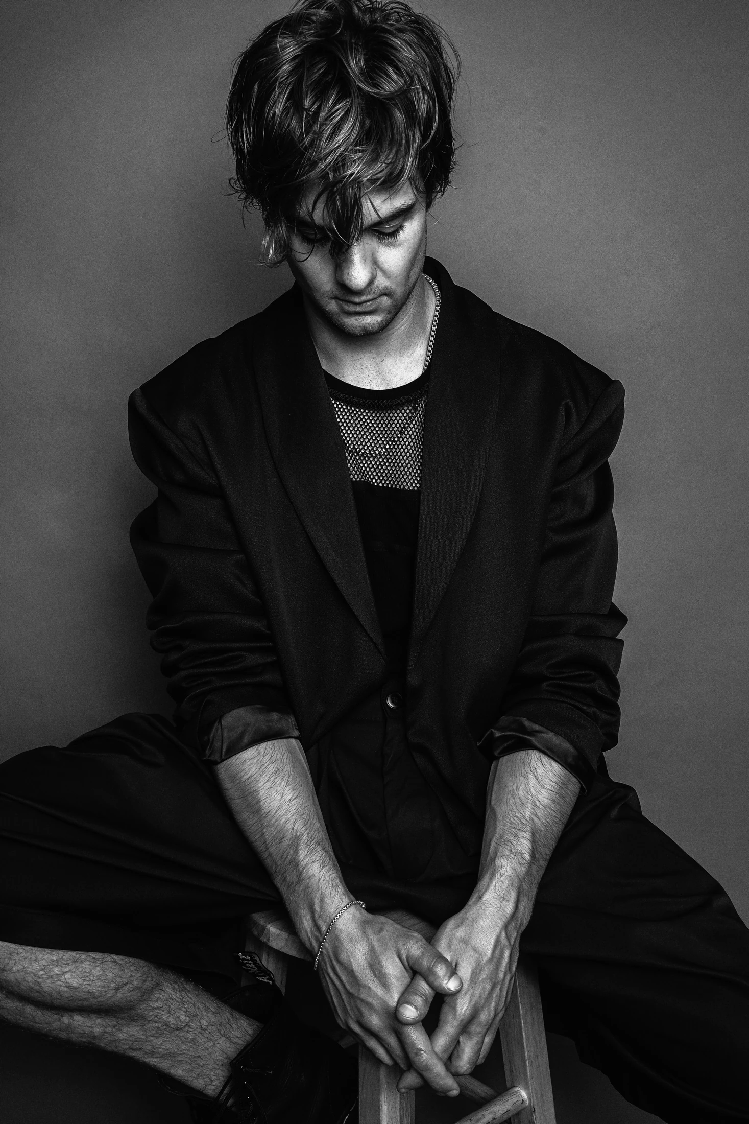 Jake Crossman seated in a black blazer in a black-and-white editorial photograph