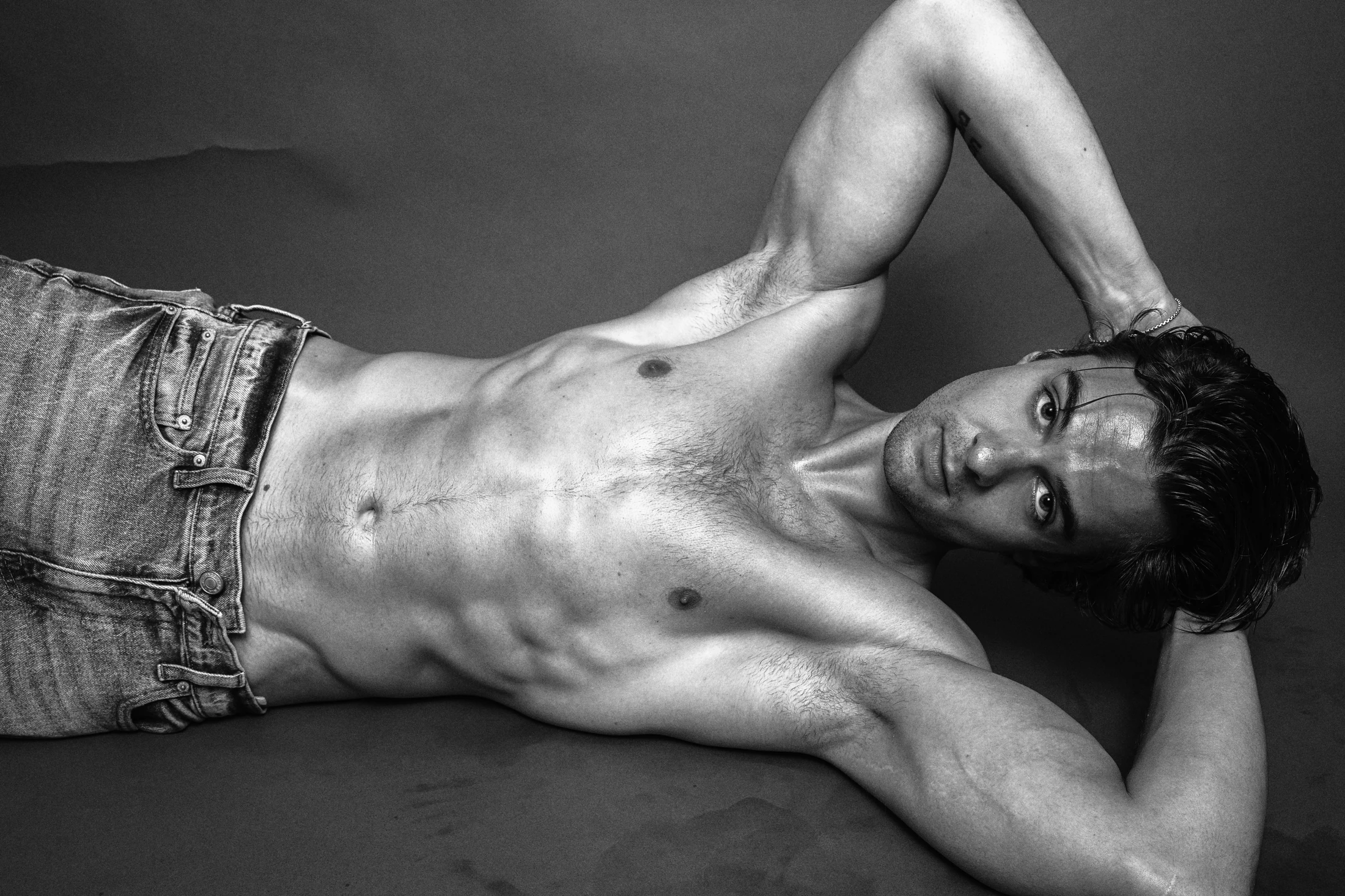 Jake Crossman reclining with one arm raised in a black-and-white editorial photograph