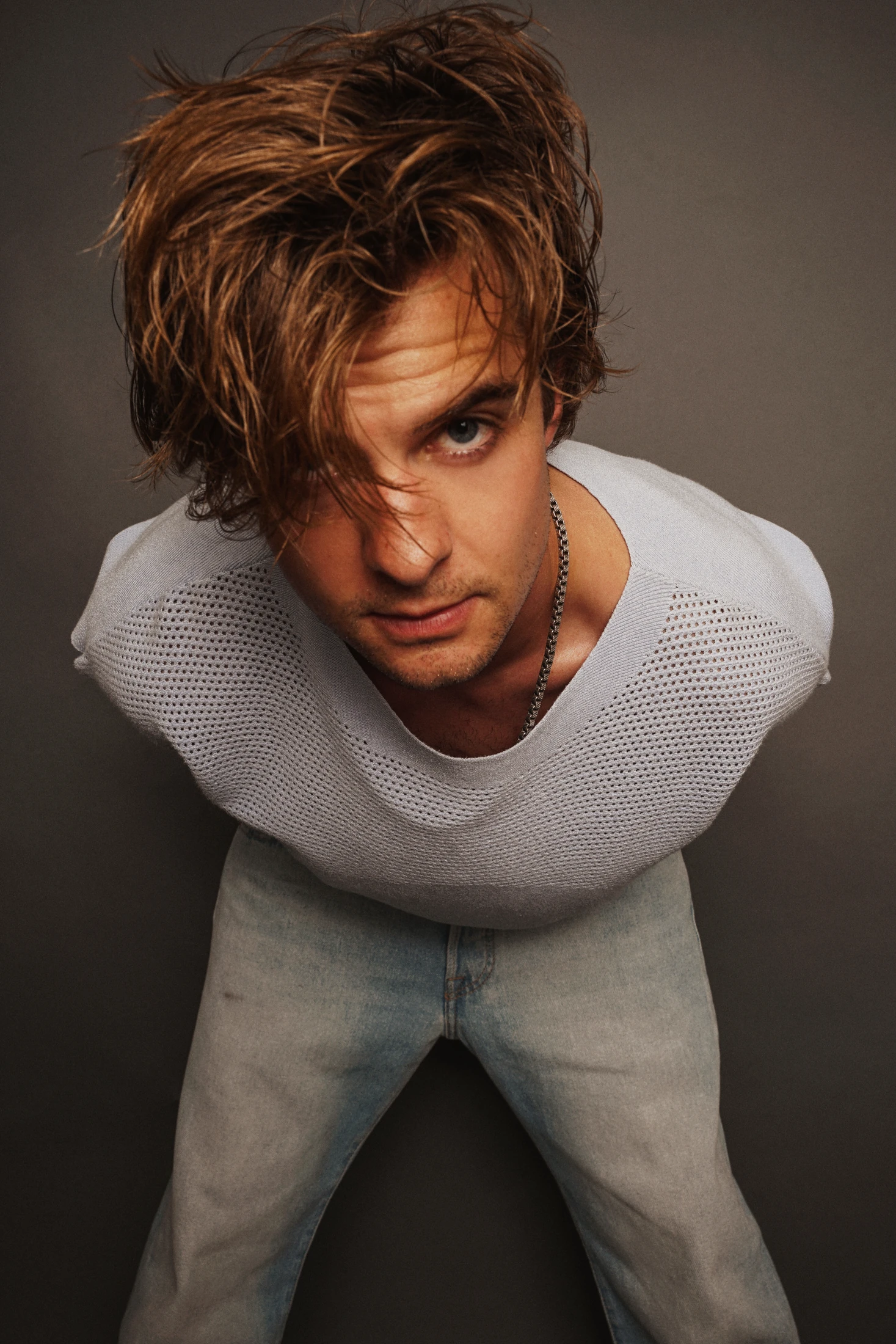 Jake Crossman leaning toward the camera in a white mesh shirt
